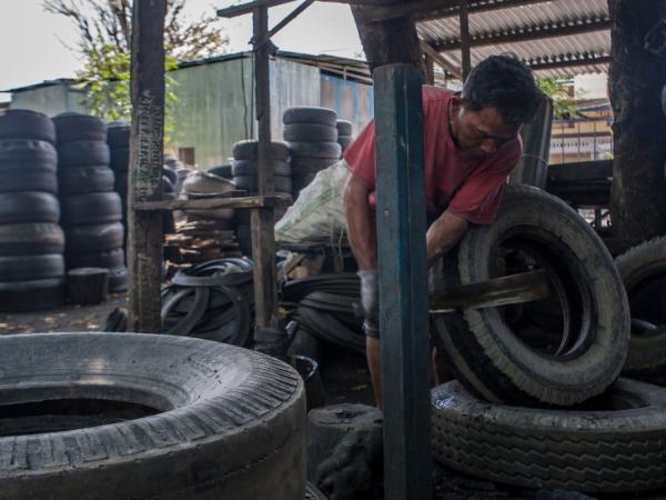 BBC Mundo: Hombre en un taller trabajando con neumáticos usados