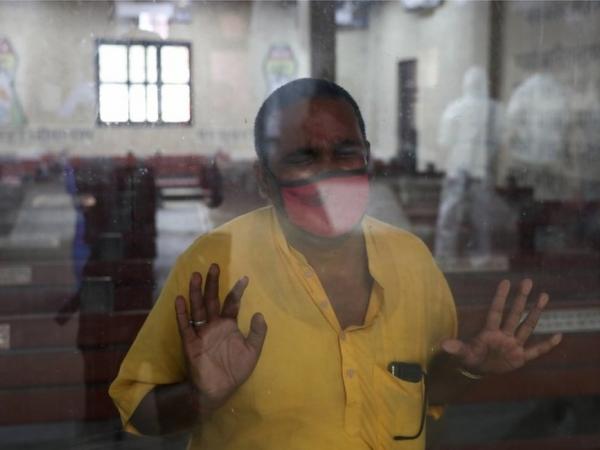 BBC Mundo: El pariente de un familiar que murió de coronavirus observa a través de una ventana cómo preparan a la víctima para su cremación en Nueva Delhi, India, 9 de abril de 2021