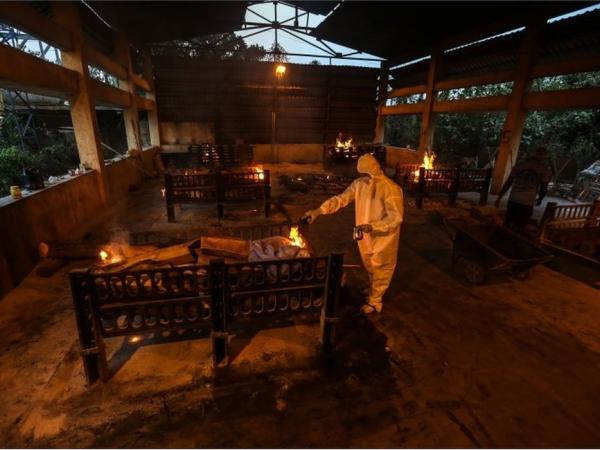 BBC Mundo: Familiares y empleados municipales practican los ritos fúnebres a las víctimas de covid-19 en un centro de cremación en Bombay, India, 13 de abril de 2021.